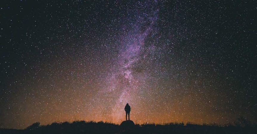 person standing in silhouette in front of the milky way galaxy in the sky